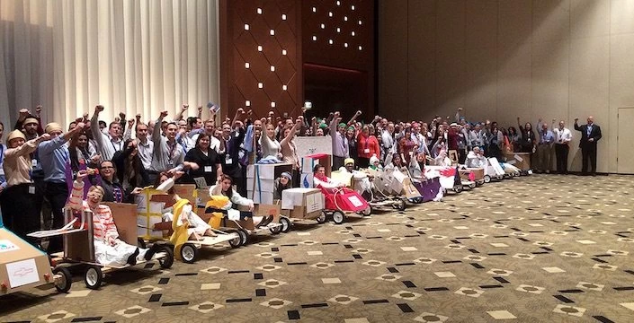A group of people posing for a picture in front of a large room.