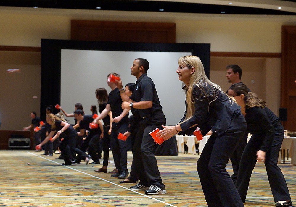 A group of people playing frisbees in a room.