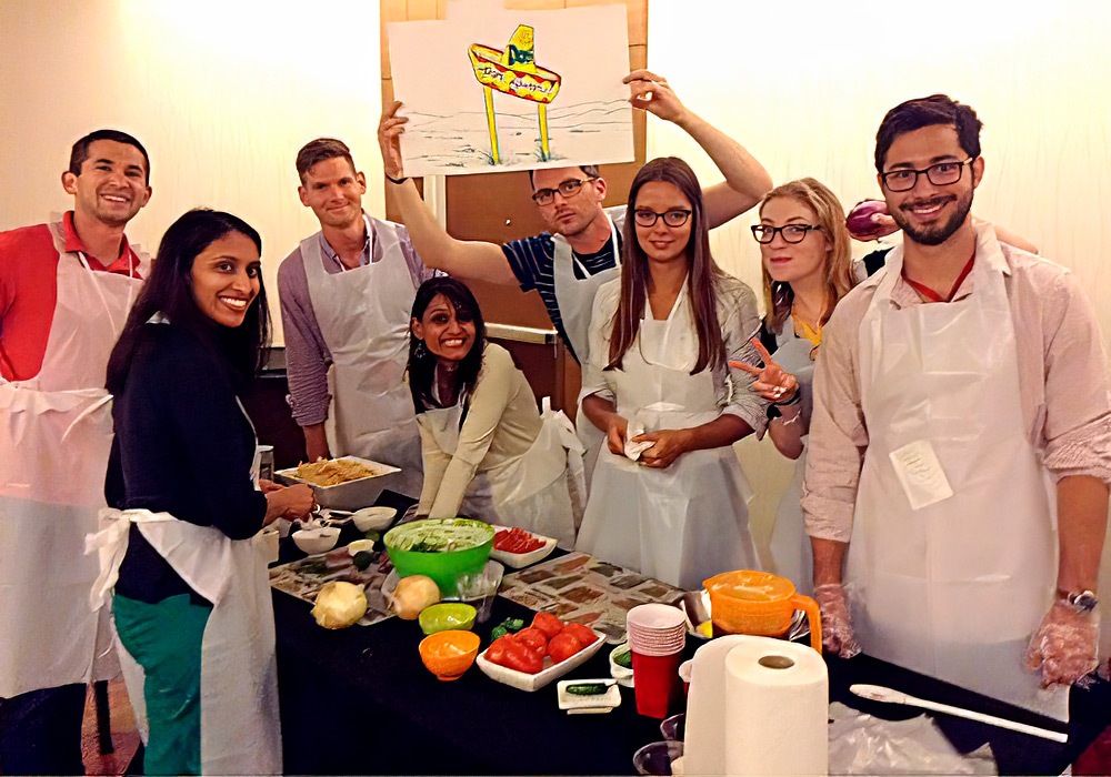 A group of people posing in front of a table with food.