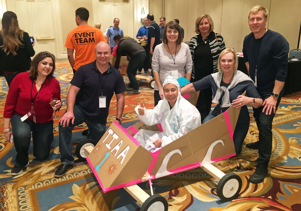 A group of people posing with a cardboard car.