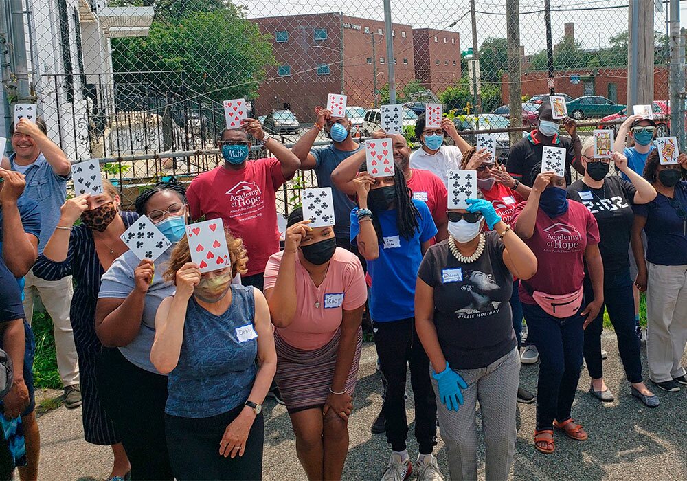 A group of people holding up cards in front of a fence.
