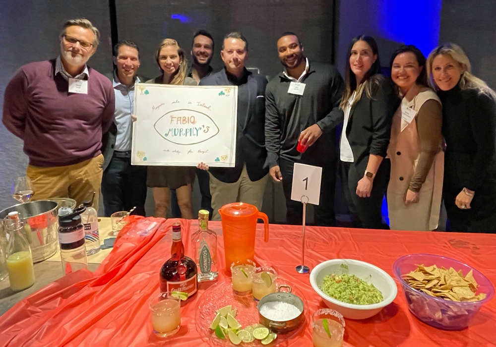 A group of people standing in front of a table with a sign.