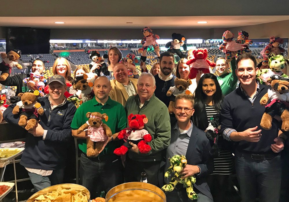 A group of people posing with teddy bears.