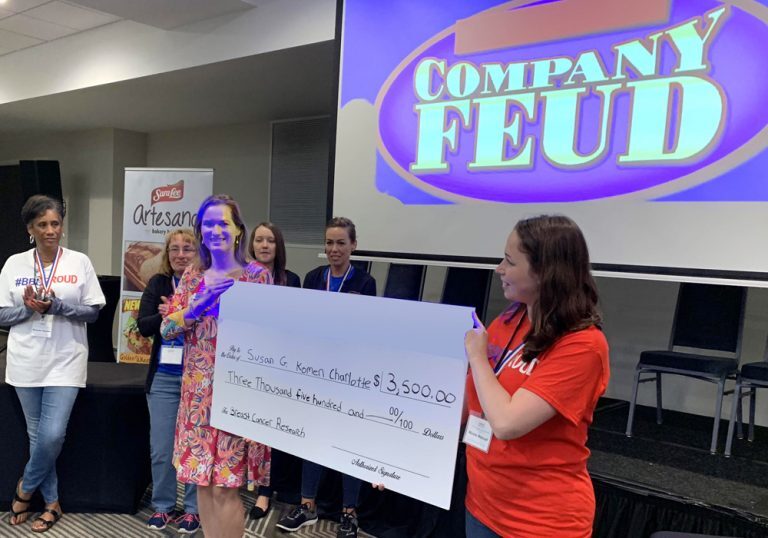 A group of people holding up a check for company feud.