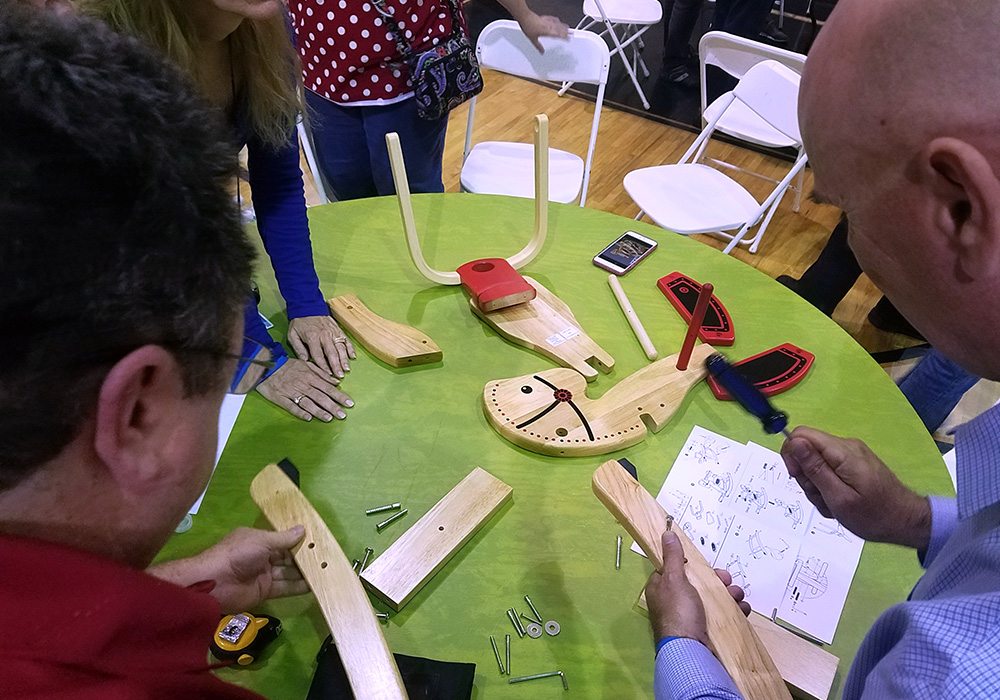 A group of people standing around a table with woodworking tools.