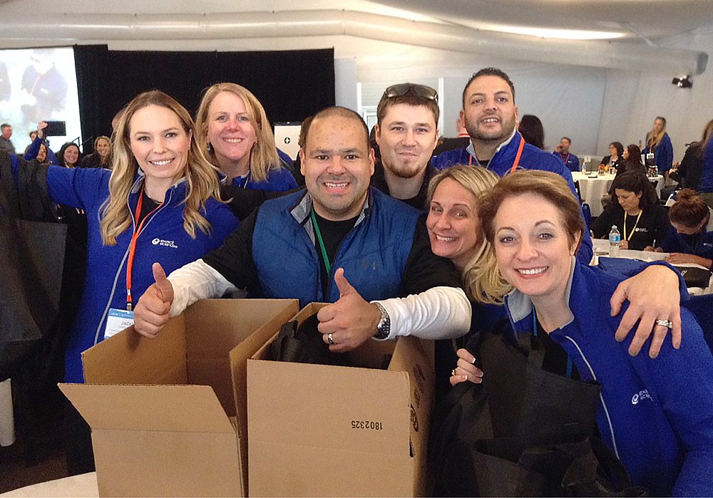 A group of people posing with boxes in front of them.