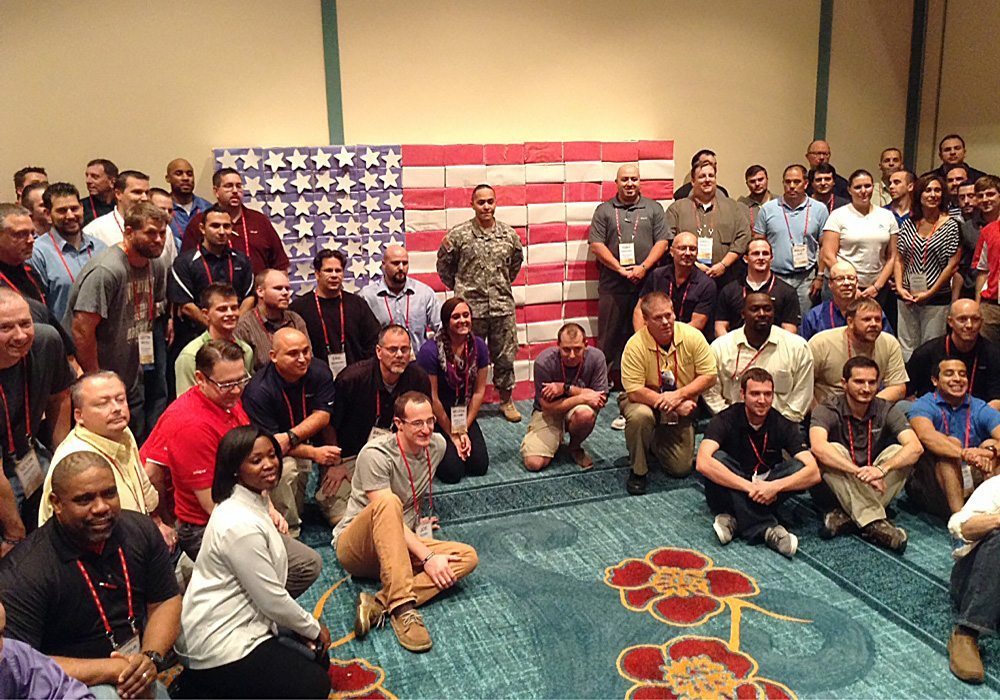 A group of people posing in front of an american flag.