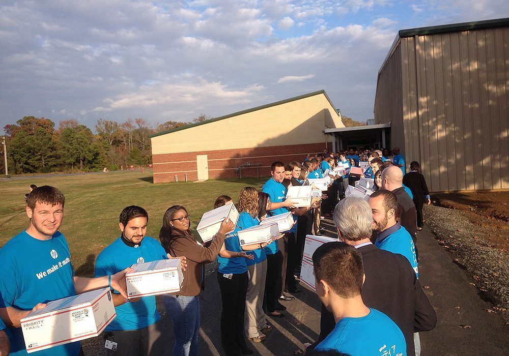 A group of people standing in a line with boxes.