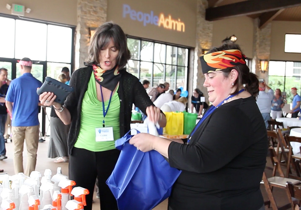 Two women standing at a table with bags in their hands.