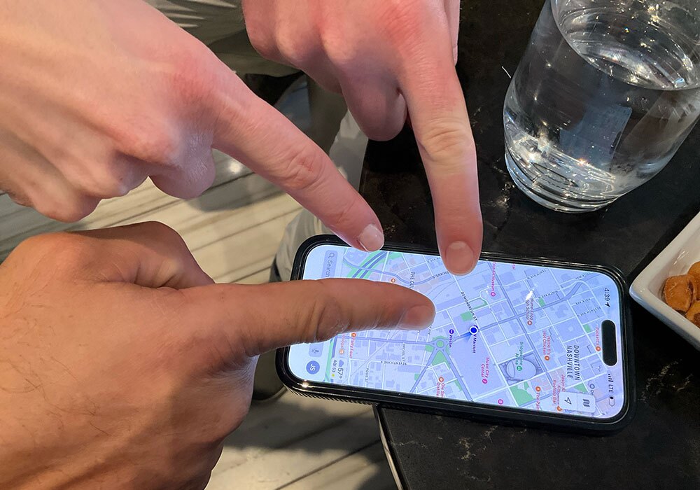 Three individuals pointing at a location on a smartphone map.