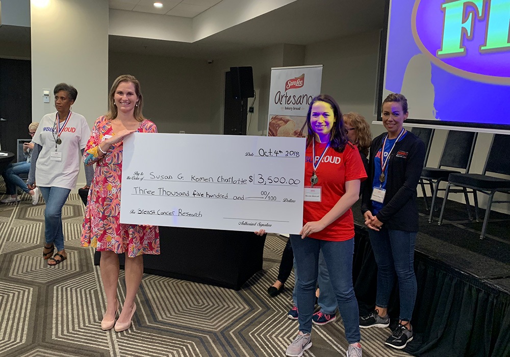 A group of people holding a check in front of a stage.