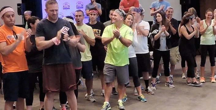 A group of people standing and clapping in a room.