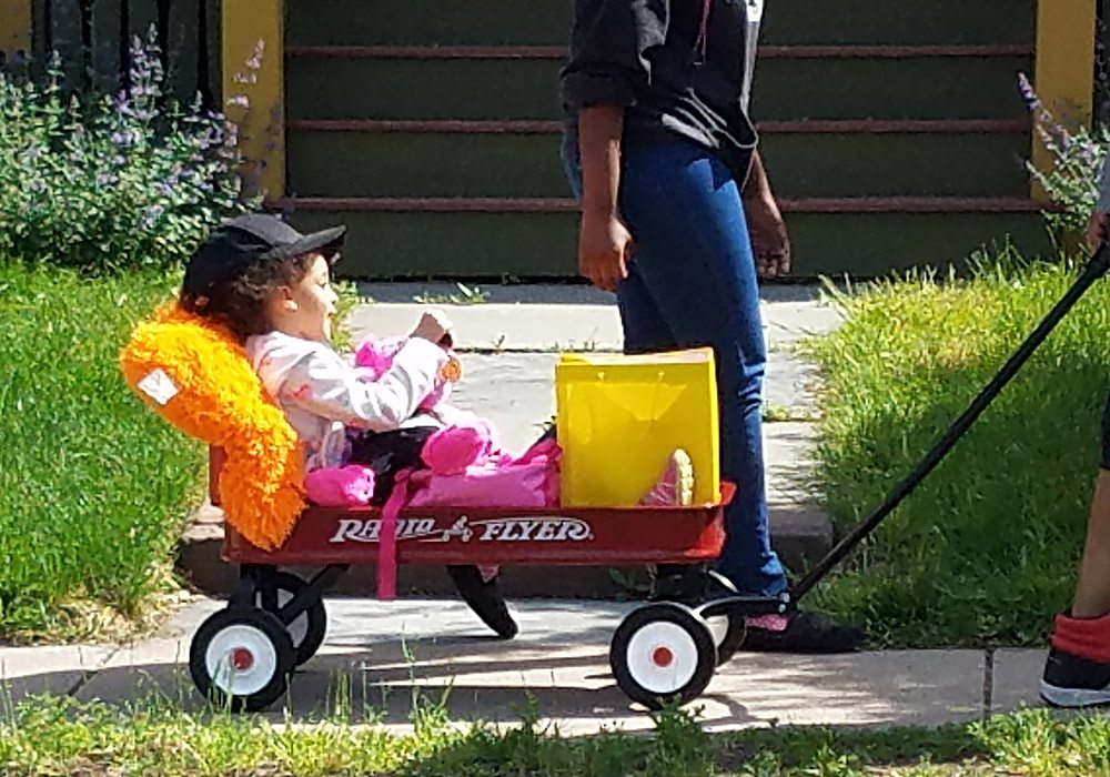 A little girl riding in a wagon.