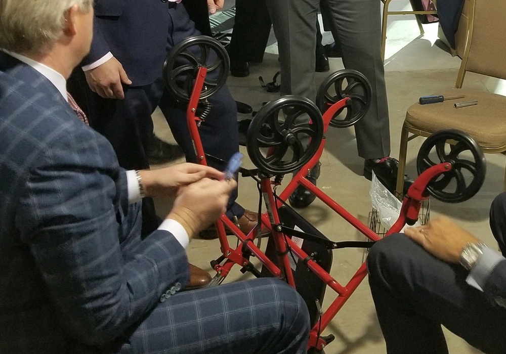 A group of people sitting around a table with a red walker.