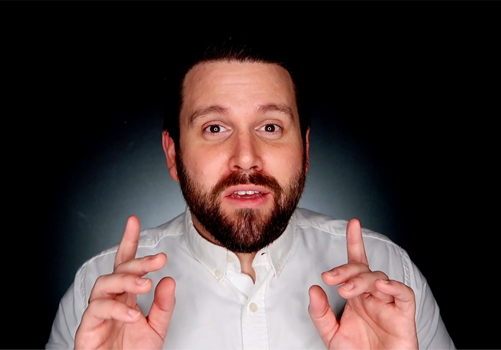 A man with a beard making a gesture with his fingers.