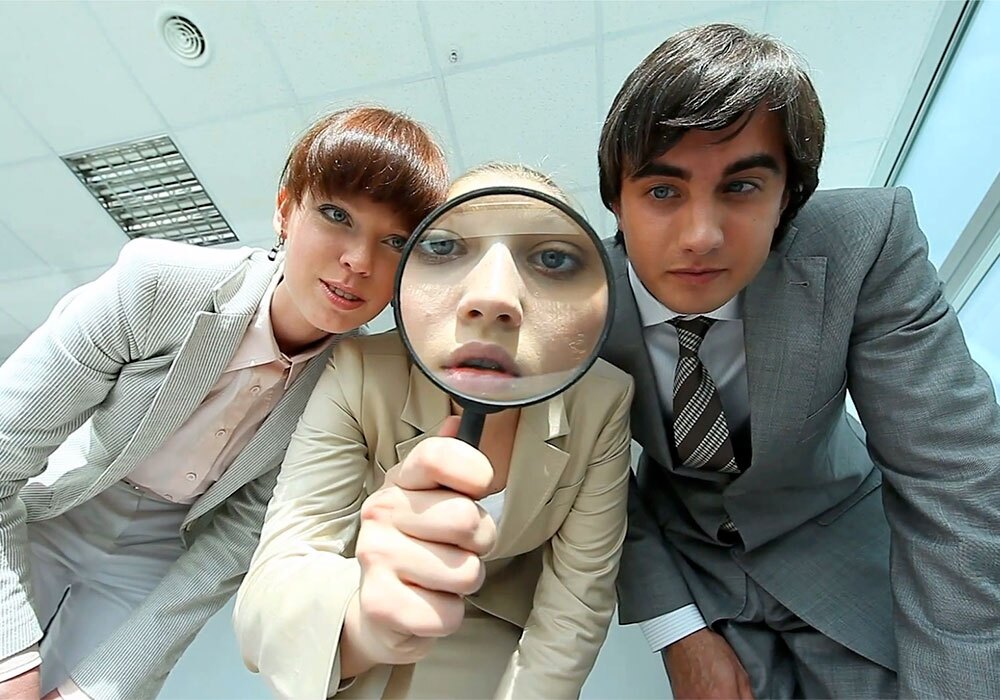 Three business people looking through a magnifying glass.