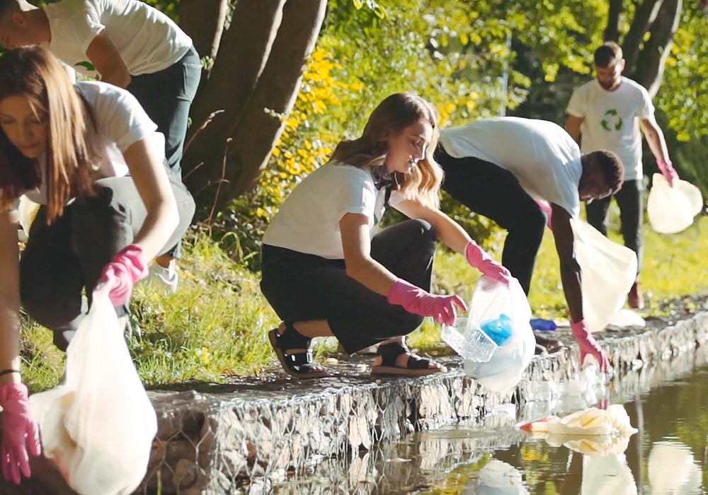 A group of people picking up trash in a river.