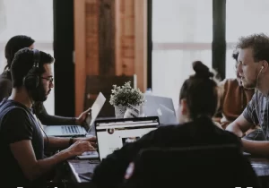 A group of people working on laptops at a table, fostering an environment to increase employee engagement.
