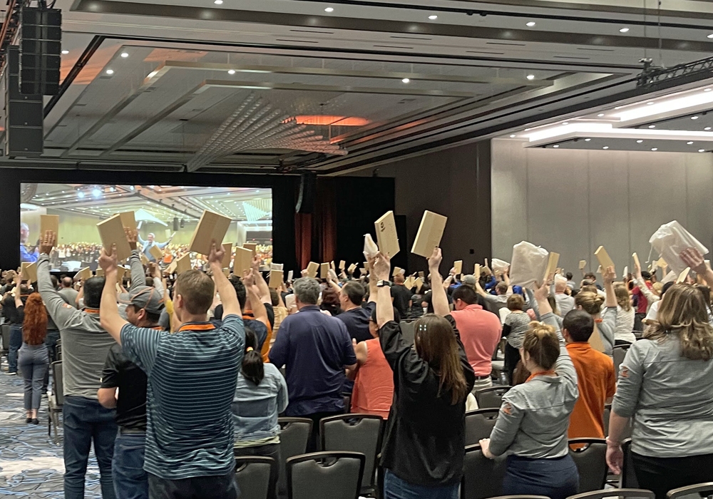 A group of people raising their hands in a conference room.