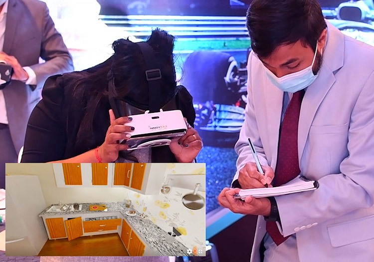 A man in a suit is writing on a piece of paper in front of a kitchen.