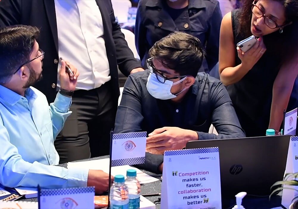 A group of people standing around a table with laptops.