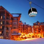 A gondola ride over a snow covered town at night.