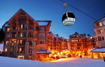 A gondola ride over a snow covered town at night.