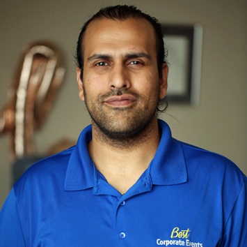 A man in a blue shirt standing in front of a room.