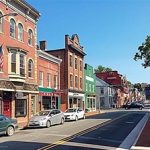 A street lined with brick buildings and parked cars.