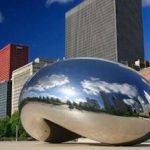 The chicago cloud gate is in the middle of a city.