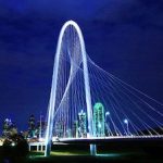 The dallas skyline at night with the bridge lit up.