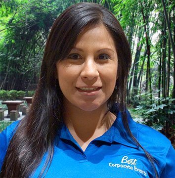 A woman in a blue shirt standing in front of a bamboo forest.
