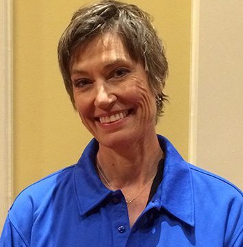 A woman in a blue shirt smiling for the camera.