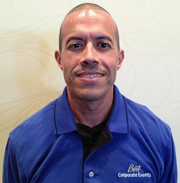 A man in a blue shirt standing in front of a wall.