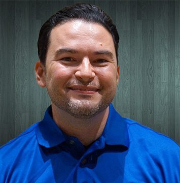 A man in a blue shirt smiling for the camera.