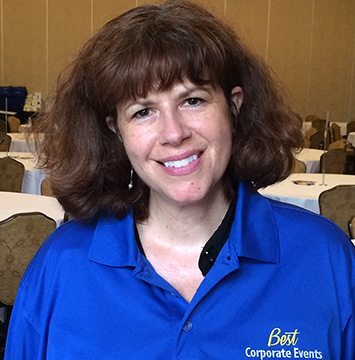 A woman in a blue shirt smiling at a table.