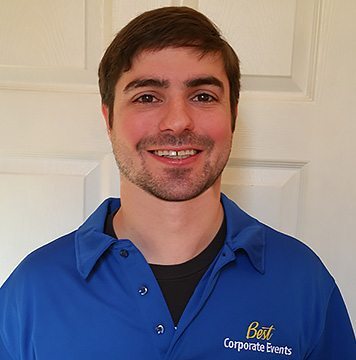 A man in a blue shirt smiling in front of a door.