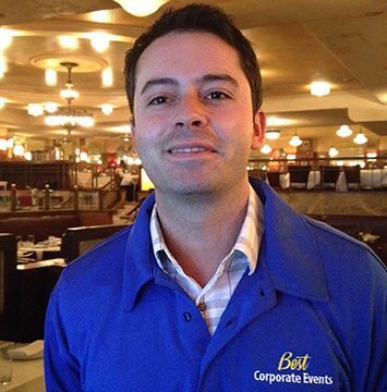 A man in a blue shirt standing in a restaurant.