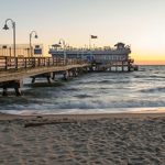 A pier on a beach at sunset.
