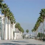 A street lined with palm trees in front of a building.