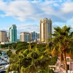 A city skyline with palm trees and boats on the water, perfect for team building in St. Petersburg.