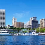 Team Building in a city with tall buildings and boats docked in the water.