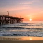 A pier in Virginia Beach with the sun setting behind it, providing a picturesque backdrop for team activities.