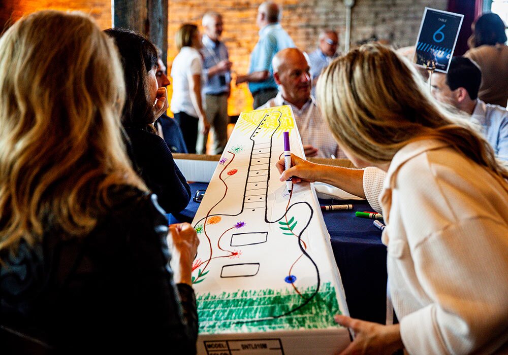 A group of people at a table with a guitar on a table.