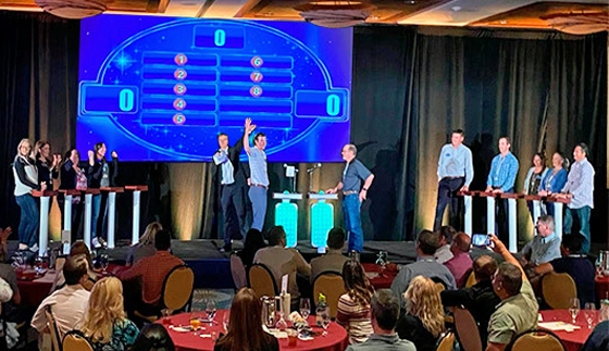 A group of people standing on a stage in front of a large screen.