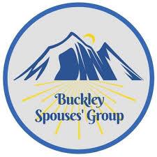 Logo of the Buckley Spouses' Group featuring a stylized blue mountain with a yellow sun and yellow rays, encircled by a blue border. The group's name is printed in the center.
