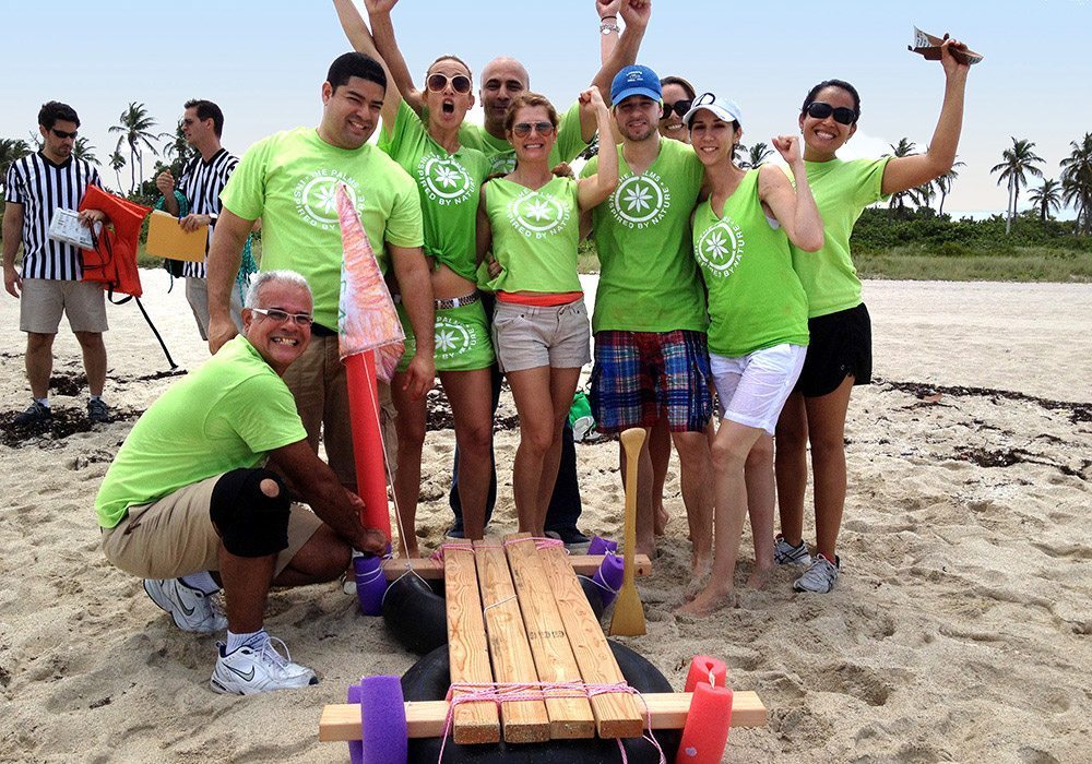 A group of people posing with a wooden boat on the beach.