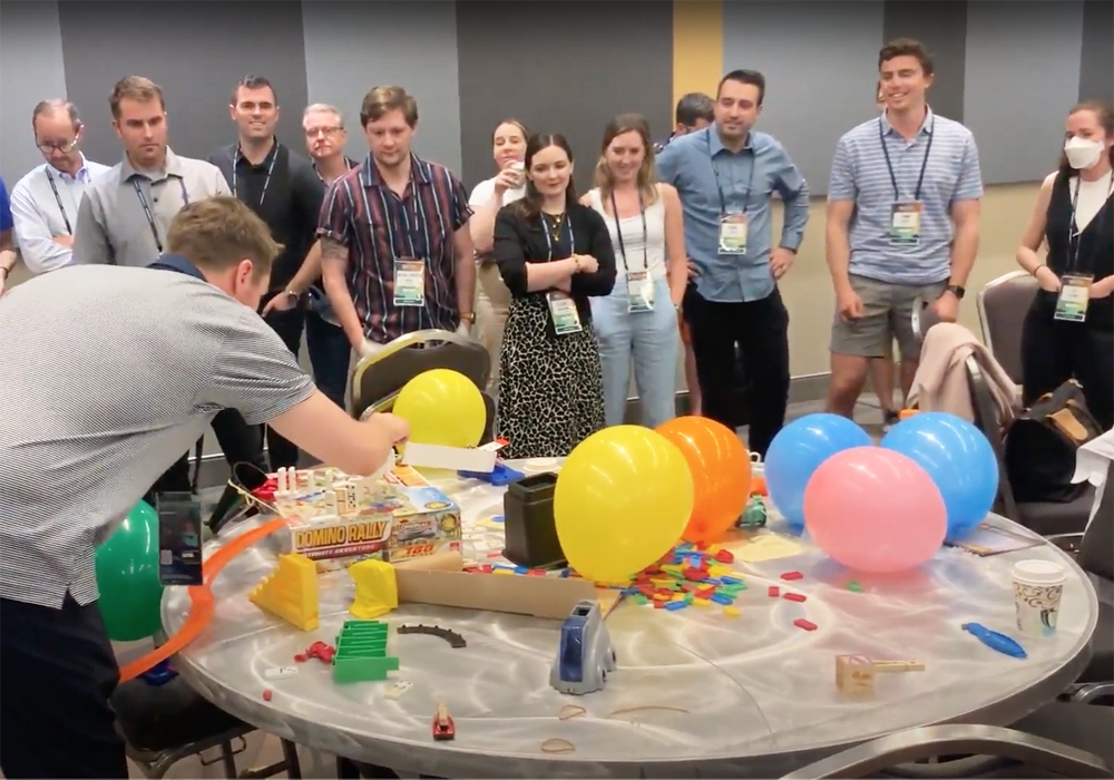 A group of people standing around a table with balloons.