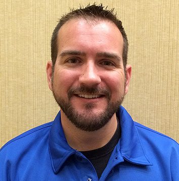 A man in a blue shirt smiling for the camera.