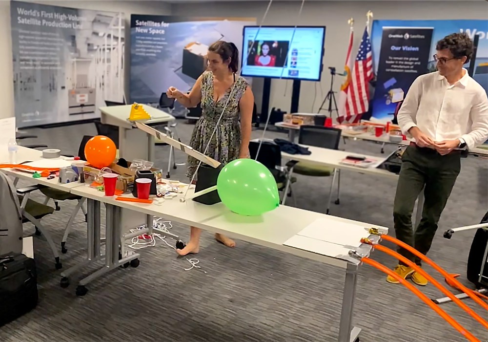 A group of people standing around a table with balloons.